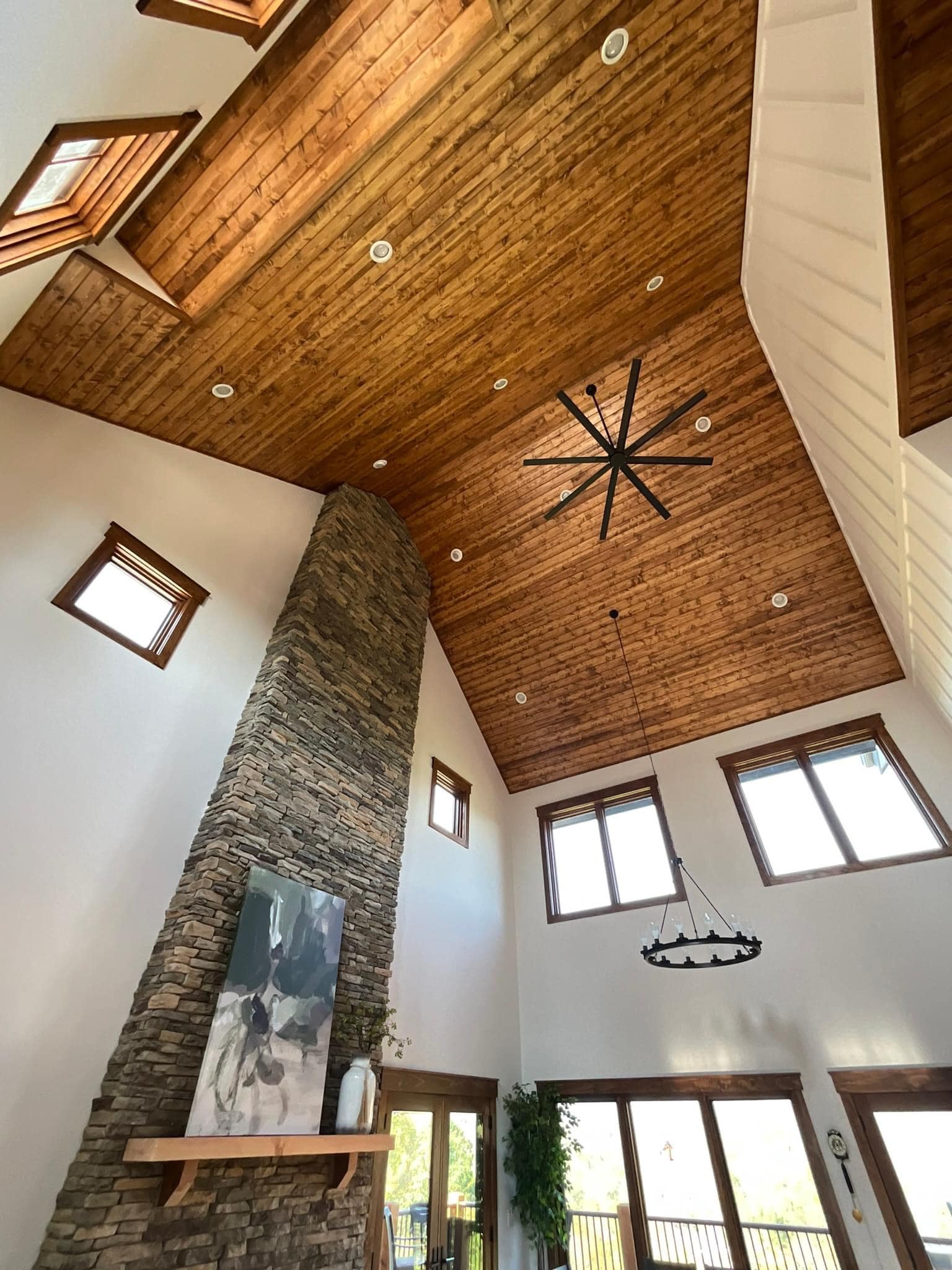Modern living room with vaulted wooden ceiling, stone fireplace, and stylish decor.